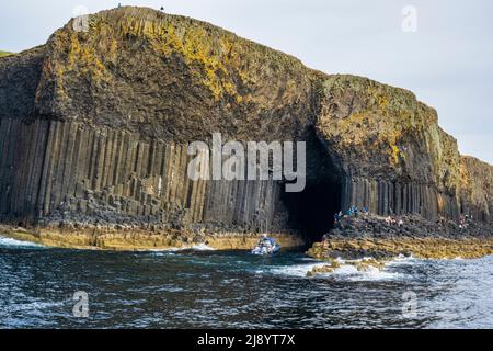 Un bateau touristique se trouve à l'entrée de la grotte de Fingal sur l'île de Staffa, dans les Hébrides intérieures, en Écosse, au Royaume-Uni Banque D'Images