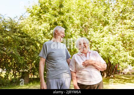 Un couple de personnes âgées qui se promette en été dans la nature s'amuse bien et rient ensemble à une blague Banque D'Images