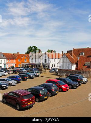 Une vue sur la place du marché et la croix de marché avec des voitures garées dans le village médiéval de Lavenham, Suffolk, Angleterre, Royaume-Uni. Banque D'Images