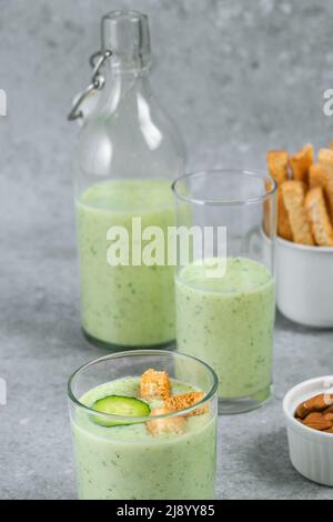 Soupe de concombre fraîche avec noix, herbes, yaourt, craquelins dans un bécher en verre sur fond gris. Nourriture végétalienne saine Banque D'Images