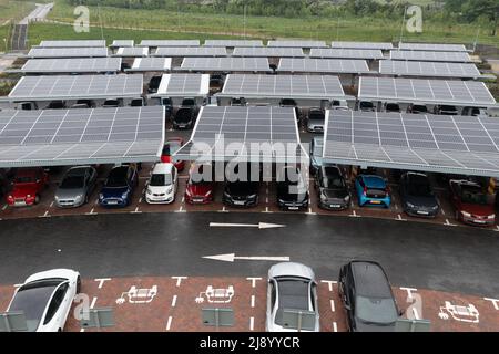 Vue aérienne au-dessus de panneaux solaires innovants situés sur un parking de voitures toits faisant bon usage de petits espaces dans une ville pour charger des voitures électriques Banque D'Images