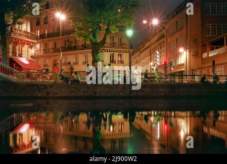 Les gens traînaient le long du canal Saint-Martin la nuit sur le quai de Valmy, avec le restaurant chez Prune et la rue Beaurepaire et la rue de Marseille derrière. Banque D'Images