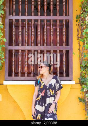 Photo verticale d'une femme de latina debout dans une ancienne façade à Carthagène en Colombie Banque D'Images