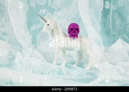 une licorne blanche brillante portant un crâne en plastique sur son dos. Photographie de la vie en couleur minimaliste et créative Banque D'Images