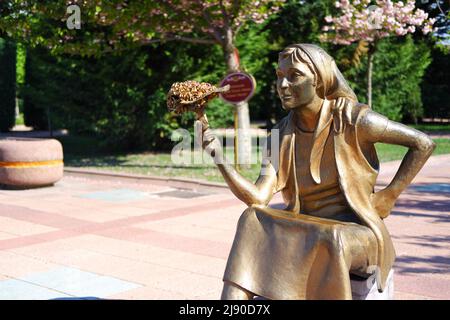 Statue de bronze de jeune femme vendant des fleurs avec bouqet en main au parc Banque D'Images