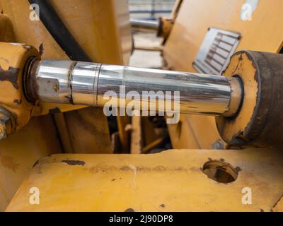 Gros plan du vérin hydraulique avec la tache d'huile du petit bulldozer sur le chantier, vue avant de l'espace de copie. Banque D'Images