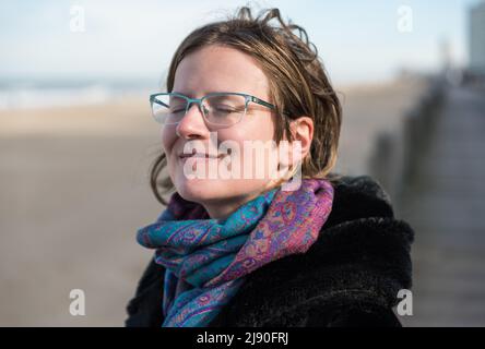 Ostende, Flandre Occidentale - Belgique 10 26 2019 Femme blanche attrayante avec des lunettes et des yeux fermés se détendant au bord de la mer Banque D'Images