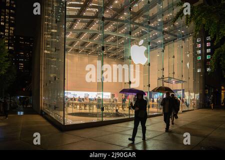 New York, NY, US-octobre 26, 2021: Les personnes avec des parasols marchent à côté de l'Apple Computer Store lors d'une nuit de pluie. Banque D'Images