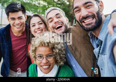 Groupe multiethnique d'amis s'amusant à prendre selfie en plein air - Focus sur le visage de l'homme central Banque D'Images