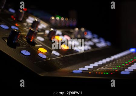 prise de vue en gros plan d'un appareil de mixage audio numérique moderne pour un mixage audio professionnel dans une salle de concert, dans un éclairage partiel faible et sélectif Banque D'Images