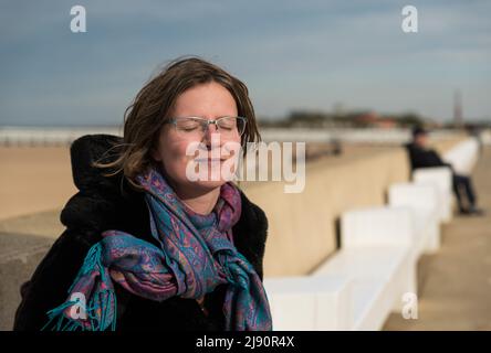 Ostende, Flandre Occidentale, Belgique- 10 26 2019 belle femme blanche avec des lunettes et des yeux fermés se détendant au bord de la mer belge Banque D'Images