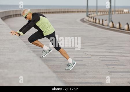 Vue côté horizontal tourné de sporty man faisant matin exercices aérobiques en plein air Banque D'Images