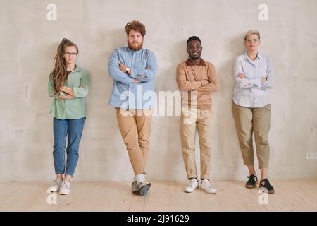 Portrait complet du contenu jeune équipe de marketing multi-ethnique confiante debout avec les bras croisés contre le mur Banque D'Images