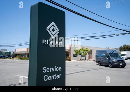 Le panneau de Rivian est visible dans un centre de service de Rivian, avec une fourgonnette de transport Ford de marque Amazon Prime passant dans les rues en arrière-plan, sur 1 mai 2022. Banque D'Images