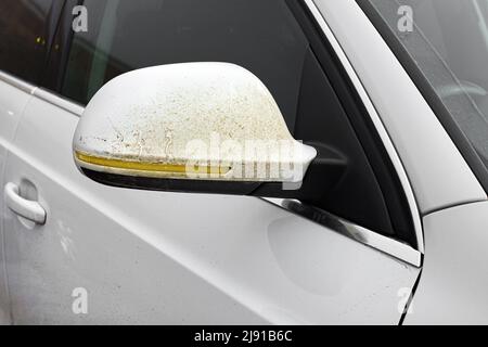 rétroviseur latéral sur la porte du conducteur recouvert d'une couche de saleté collée sur une voiture blanche sale avec clignotants jaunes sur le panneau de carrosserie du rétroviseur extérieur Banque D'Images