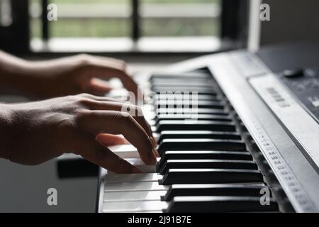 jeune latino-américain créant une chanson sur un synthétiseur. prise de vue détaillée des mains d'un musicien jouant du piano. passe-temps à la maison dans la lumière naturelle. concep musical Banque D'Images