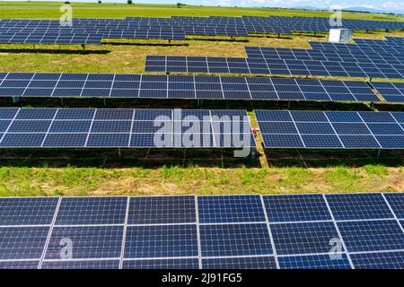 Vue aérienne les panneaux photovoltaïques se trouvent sur un terrain vert dans le nord de la Grèce. Ciel bleu réfléchissant dans les rangées de panneaux solaires. Station électrique alternative futuriste. S Banque D'Images