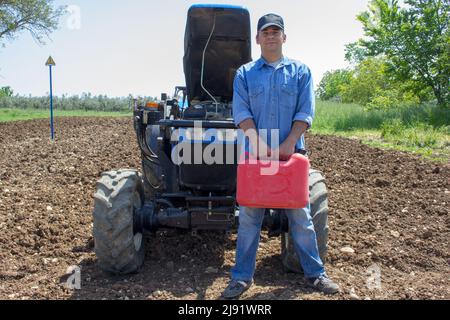 Fermier avec une bidon d'essence dans sa main et le tracteur derrière. Grève sur les carburants coûteux dans le secteur agricole Banque D'Images
