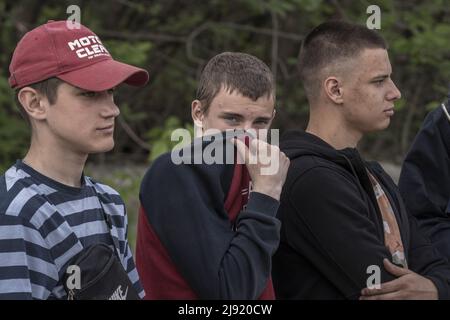 Malaya Rohan, Ukraine. 19th mai 2022. On voit de jeunes adolescents observer que des hommes tirent les corps de deux soldats russes morts d'où il a été enterré dans une cour avant de personnes à Mala Rohan, en Ukraine, le jeudi 19 mai 2022. Mala Rohan est un petit village repris par les forces ukrainiennes, après l'attaque de la Russie contre l'Ukraine. Photo de Ken Cedeno/UPI crédit: UPI/Alay Live News Banque D'Images