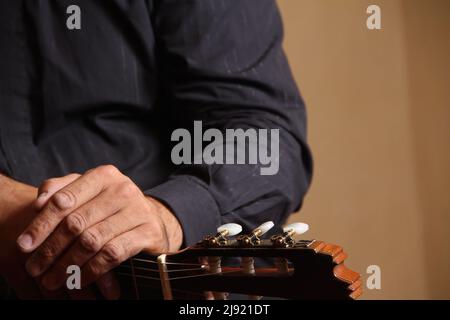 Hommes guitaristes penchent sur l'écrou et les capstans d'une guitare acoustique dans le centre d'Athènes, Grèce. Banque D'Images