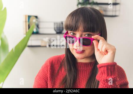 Portrait de la jeune femme caucasienne à cheveux foncés prenant des lunettes rose foncé copier espace accueil arrière-plan . Photo de haute qualité Banque D'Images