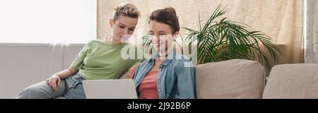 joyeux pansexe personnes assis sur un canapé et regarder un film sur un ordinateur portable, bannière Banque D'Images