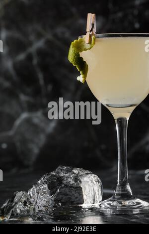 Cocktail de gimlet Kamikaze en verre martini avec glace sur fond de marbre noir. Cocktails alcoolisés aux agrumes Banque D'Images