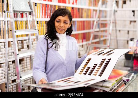 Femme choisissant la couleur de cheveux de la palette au magasin Banque D'Images