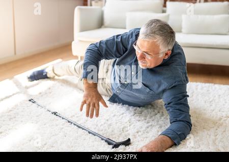 Man tombé sur tapis avec bâton de marche Banque D'Images
