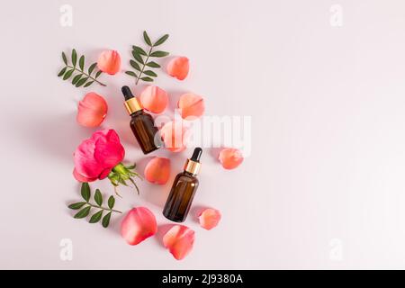 deux flacons cosmétiques avec pipette compte-gouttes sur le fond des pétales d'une rose de thé rouge. cosmétiques naturels. soins de la peau supplémentaires Banque D'Images