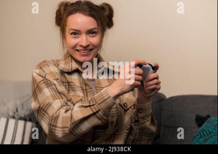 Joyeux gamer fille dans une chemise à carreaux avec un joystick joue des jeux vidéo. Réalité virtuelle, cyberespace, culture de la jeunesse, communication avec les amis, passe-temps, h Banque D'Images