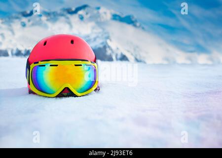 Casque rose avec masque de ski dans la neige au-dessus de la chaîne de montagnes Banque D'Images