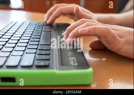 Un homme aveugle utilise un ordinateur doté d'un écran en braille et d'un clavier d'ordinateur. Périphérique inclus. Banque D'Images