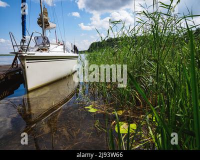 voilier amarré près de l'ancienne jetée en bois sur une rive du lac pendant une journée ensoleillée d'été Banque D'Images