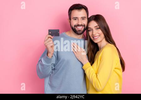 Photo d'une jolie dame, un gars adorable, montrant une carte de débit en plastique isolée sur fond rose Banque D'Images