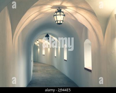 Le couloir du château est éclairé par un éclairage au plafond. Intérieur d'un long couloir avec murs et arches blancs, foyer sélectif Banque D'Images