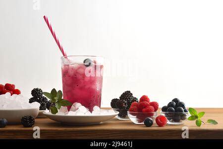 Boire avec des baies aux fruits et de la glace autour avec fond blanc isolé. Vue avant. Composition horizontale. Banque D'Images