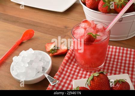 Granita de fruits avec fraises mûres et beaucoup de glace sur une table en bois avec un bol de glace et un panier rempli de fraises. Vue en hauteur. Co. Horizontale Banque D'Images