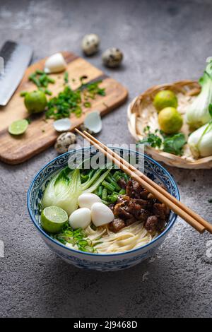 Soupe asiatique traditionnelle aux nouilles avec bok choi et poulet dans un bol en céramique. Banque D'Images
