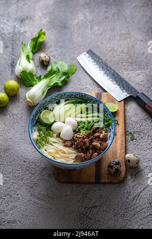 Soupe japonaise de ramen avec poulet, œuf, ciboulette et bok choy sur fond de béton. Banque D'Images