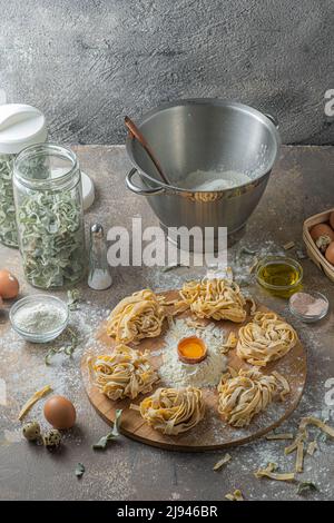 Pâtes de tagliatelle fraîchement préparées avec œufs et farine sur bois Banque D'Images