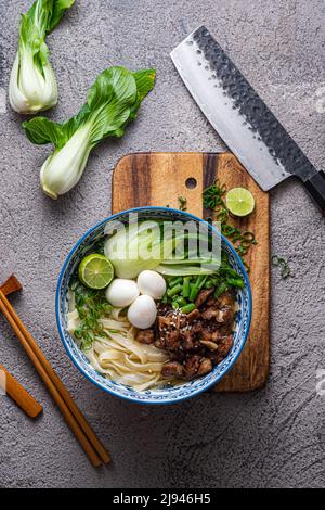 Soupe japonaise de ramen avec poulet, œuf, ciboulette et bok choy sur fond de béton. Banque D'Images