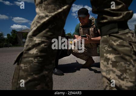 Barvinkove, Kharkiv Oblast, Ukraine. 20th mai 2022. Le maire de Barvinkove, Alexander Balo, s'agenouillant à gauche, regarde une vidéo avec un soldat qui s'est arrêté pour le saluer à Barvinkove, en Ukraine, le 20 mai 2022. « Les Ukrainiens ne veulent pas négocier avec les Russes », a-t-il déclaré. "Nous voulons tuer leurs troupes. Ils seront très désolés d'entrer dans notre pays et le regretteront. (Image de crédit : © Daniel Carde/ZUMA Press Wire) Banque D'Images