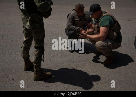 Barvinkove, Kharkiv Oblast, Ukraine. 20th mai 2022. Le maire de Barvinkove, Alexander Balo, au centre, regarde une vidéo avec un soldat qui s'est arrêté pour le saluer à Barvinkove, en Ukraine, le 20 mai 2022. « Les Ukrainiens ne veulent pas négocier avec les Russes », a-t-il déclaré. "Nous voulons tuer leurs troupes. Ils seront très désolés d'entrer dans notre pays et le regretteront. (Image de crédit : © Daniel Carde/ZUMA Press Wire) Banque D'Images