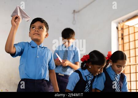 adolescent jouant en jetant un avion de papier dans la salle de classe - concept de style de vie de l'enfance, le développement, le méfait et l'apprentissage Banque D'Images