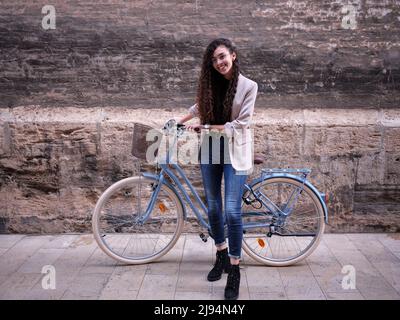 Femme arabe posant avec son vélo sur son chemin à la cafétéria pour travailler, portrait horizontal Banque D'Images