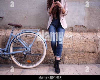 vue rapprochée d'une femme discutant sur son téléphone à côté de son vélo dans la rue, découpe horizontale Banque D'Images