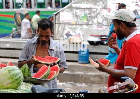 Dhaka, Bangladesh - 20 mai 2023 : les tireurs de pousse-pousse mangeant de la pastèque pendant une chaude journée d'été à Dhaka, au Bangladesh. Banque D'Images