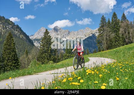 Belle femme senior à cheval sur son vélo électrique de montagne sur l'ancienne route de Gaicht Pass de Lech Valley jusqu'à la vallée de Tannheim dans le Tyrol, Autriche Banque D'Images