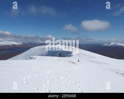 Vue sur les pistes de Fionn Bheinn avec des corniches, et le long de Strath Bran, avec un alpiniste laissant des empreintes de pas dans la neige. Banque D'Images